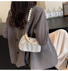 Silver pleated cloud bag with wooden handle and pearl chain strap shown on model
