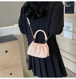 Detail of pink pleated cloud bag with wooden handle and white pearl chain strap decoration