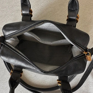 Top view of black leather bowling bag with chevron lining and golden hardware details