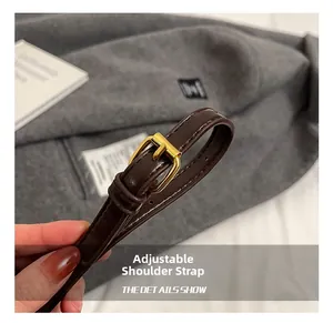 Close-up of adjustable brown leather shoulder strap with gold metal buckle and stitching