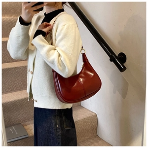 Deep red leather crescent underarm bag with gold chain strap shown in mirror selfie