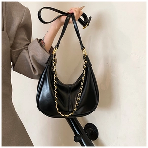Close-up of black crescent hobo bag with gold chain and smooth leather texture