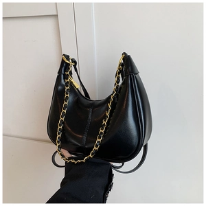 Detail of a black crescent hobo bag featuring a chunky gold chain and a smooth leather texture