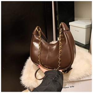Detailed view of the dark brown glossy leather underarm bag with gold chain strap