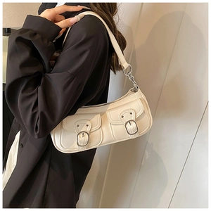 Detail of cream leather shoulder bag with dual front flap pockets and silver metal buckles
