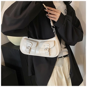 Close-up of cream white retro bag featuring dual front pockets and silver buckle hardware