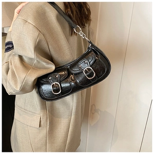 Detail of black distressed leather motorcycle bag with silver buckles on shoulder