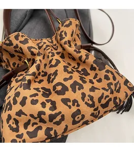 Top view of leopard print bucket bag with brown leather drawstring on a knit background