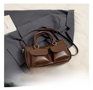 Détail d'un sac à main rétro en similicuir marron avec deux poches avant sur costume