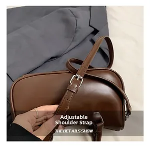 Détail de la bandoulière réglable avec boucle argentée sur le sac Boston marron