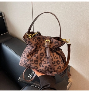 Detail of leopard print bucket bag with brown leather strap and golden hardware accents
