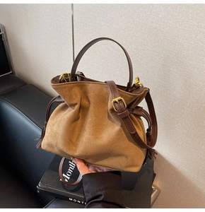 Detail of suede bucket bag with leather strap, drawstring closure and tassel decor