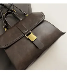 Detail of dark brown vintage briefcase bag with contrast stitching and metal buckle
