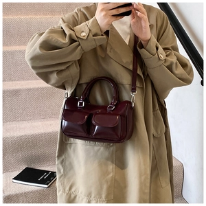 Détail du sac Boston en cuir verni bordeaux foncé avec poches avant et ferrures argentées