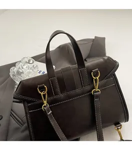Close-up of vintage brown leather handbag with gold metal hardware and white stitching details