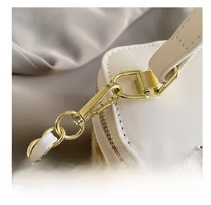Close-up of golden hardware hook and woven texture on a white leather handbag