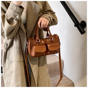Gros plan du sac Boston marron brillant avec poches avant et bandoulière réglable