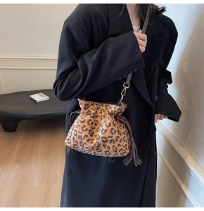 Detail of leopard print bucket bag with drawstring tassels and brown leather strap on model