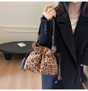 Detail of leopard print bucket bag featuring brown leather drawstring and tassel charms