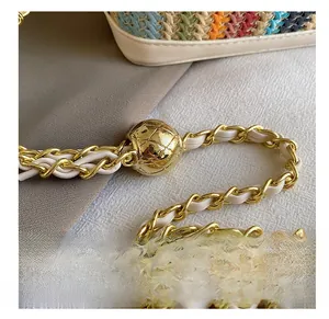 Detail of colorful woven handbag with a golden rhombus ball chain adjuster and leather strap