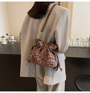 Leopard print bucket bag with long leather strap and tassel detail on a city model