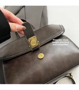 Detail of vintage brown leather bag showing the magnetic buckle and contrast stitching