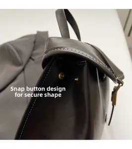 Detail view of brown leather backpack with contrast stitching and secure gold snap button