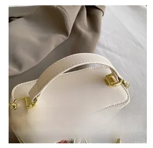 Detail of comfortable white leather handle with gold hardware on striped box bag