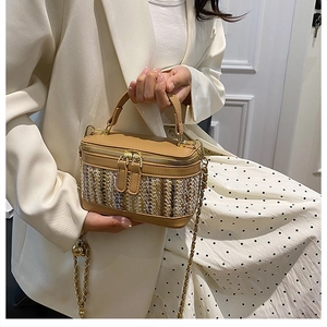 Detail view of woven leather vanity case bag with gold chain strap on model