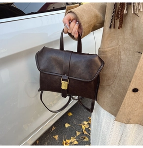 Detail of vintage brown leather backpack showing contrast stitching and metal buckle