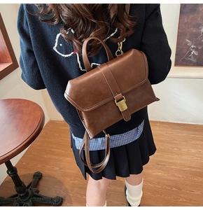 Brown vintage faux leather satchel with metal buckle shown on a model in a natural setting