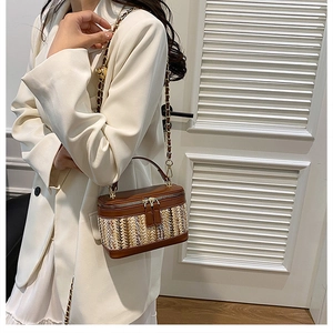 Brown leather and straw woven box bag with golden chain strap on a person