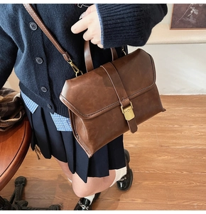 Detail of vintage brown faux leather briefcase featuring retro gold buckle and top handle