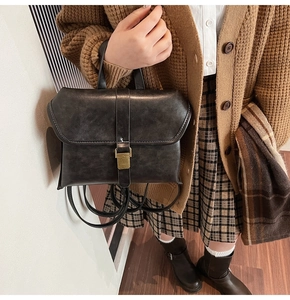 Detail of black vintage briefcase bag with matte leather texture and gold buckle