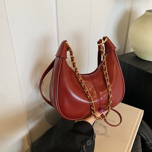 Deep red glossy leather crescent shoulder bag with golden chain handle and slim strap