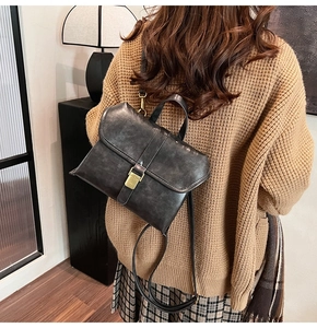 Close-up of vintage denim texture and distressed metal buckle on women's briefcase backpack