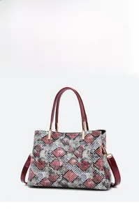 Detail of multi-color snakeskin texture on tote bag with red handles and gold hardware