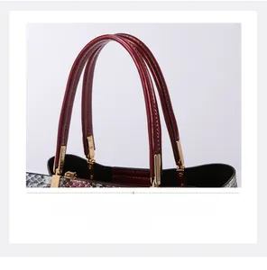 Close-up of snakeskin pattern handbag with polished red-brown handles and gold hardware