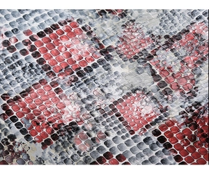 Macro shot of faux snakeskin leather texture with red, black, and gray scale pattern