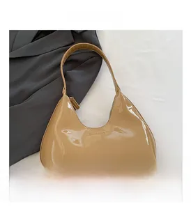 Close-up of beige glossy patent leather hobo bag with embossed Cult Gaia logo on the front