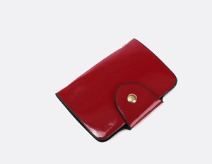 Detail of red patent leather wallet with elegant gold metal buckle and black edge finish