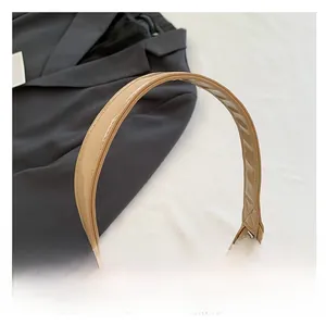 Macro detail of glossy beige faux leather shoulder bag with smooth polished texture