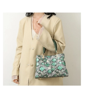 Detail of green faux snake skin texture and golden protective studs on the bottom of the tote