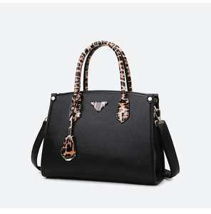 Detail of black pebbled leather tote with leopard print handle and metallic triangle plate