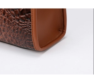 Close-up of crocodile pattern stitching and smooth leather texture on handbag corner