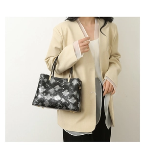 Detail of silver geometric grid pattern tote bag with gold metal hardware and black handles