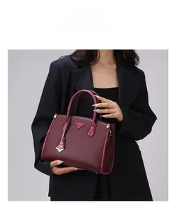 Detail of wine red tote featuring pebbled leather texture and crocodile trim accents