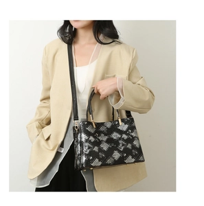 Detailed view of snake skin print handbag with golden hardware and adjustable strap