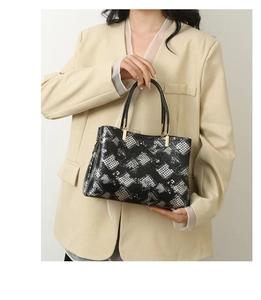 Detail of snake print tote bag featuring black handles and gold hardware on beige blazer
