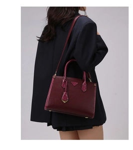 Detail of burgundy leather tote bag with lizard texture accents worn by a model